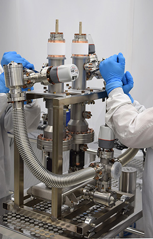 Clean room technicians work on a coupler assembly at the Beverly Microwave Division